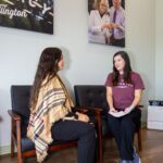 Women seated under pharmacy wall art.