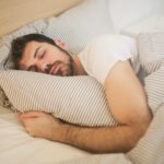 Person resting in bed with striped sheets
