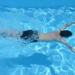 Person swimming in clear blue pool