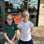 Children wearing eclipse glasses outside pharmacy