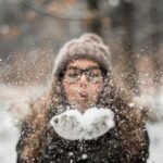 Woman blowing snow in winter forest