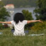 Woman meditating on grass by lake